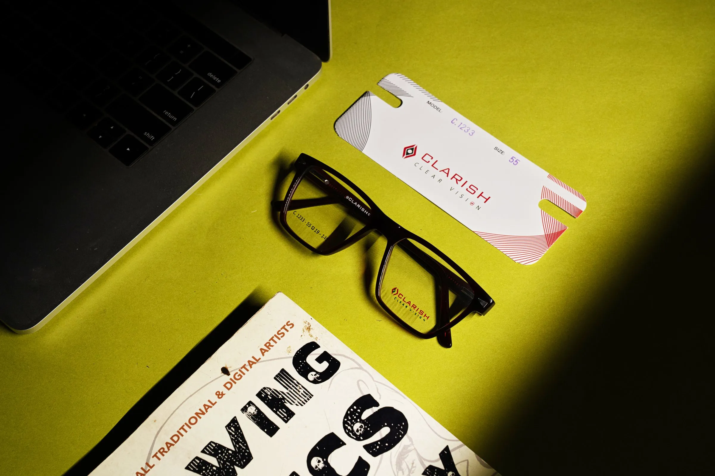 A Clarish™ acetate frame photographed with its branded sleeve on a work desk