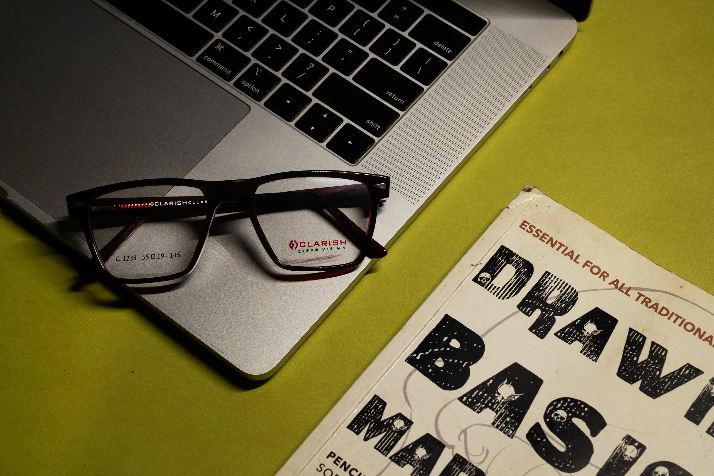 A tortoiseshell Clarish™ acetate frame resting on a laptop in a working environment