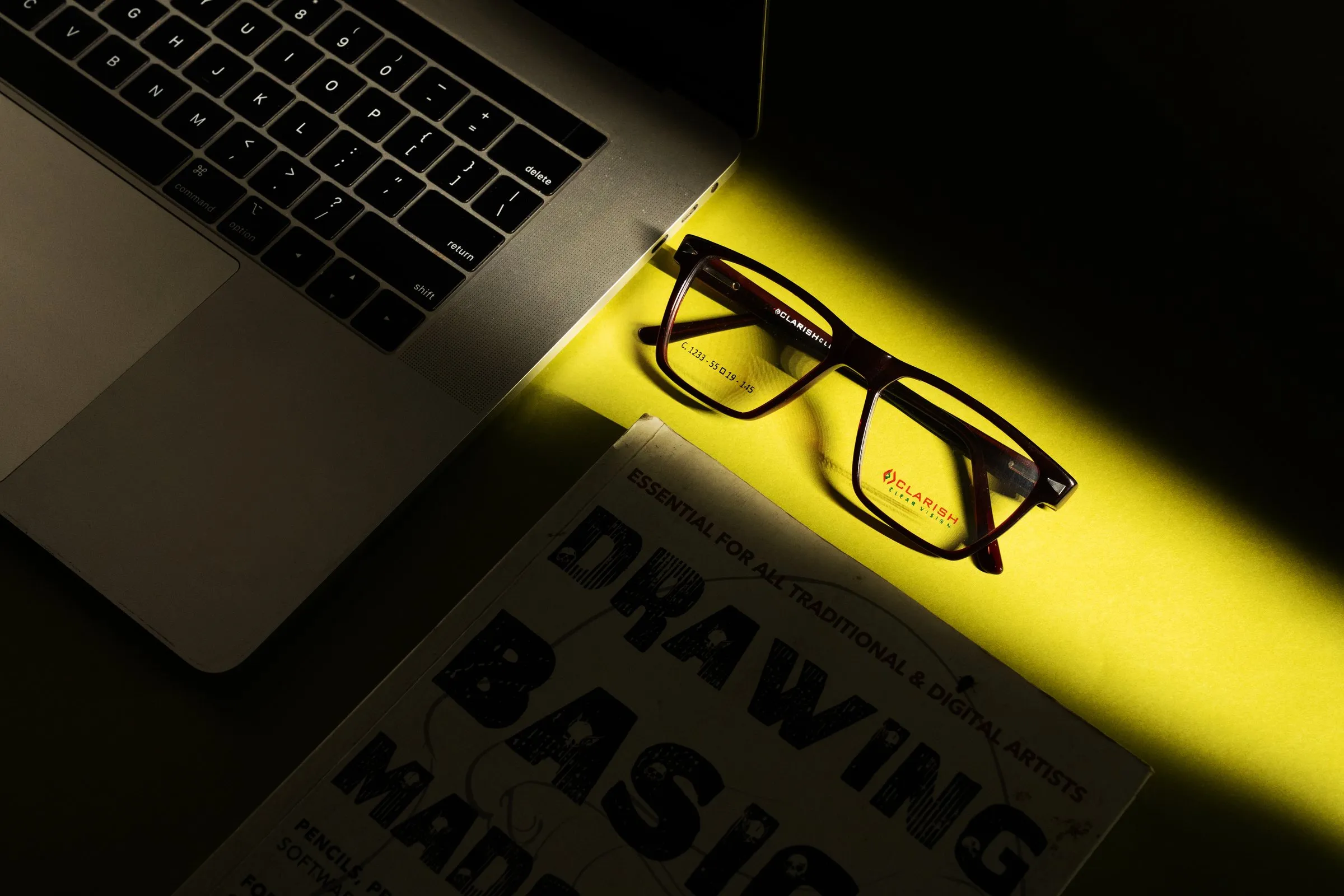 A Clarish™ acetate optical frame lit in a shaft of light on a studio surface